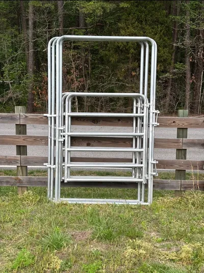 Galvanized 4-foot light bow gates stacked against a wood fence
