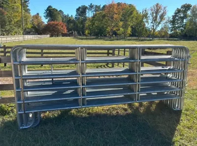 Galvanized 5x12 light corral panels stacked in a pasture