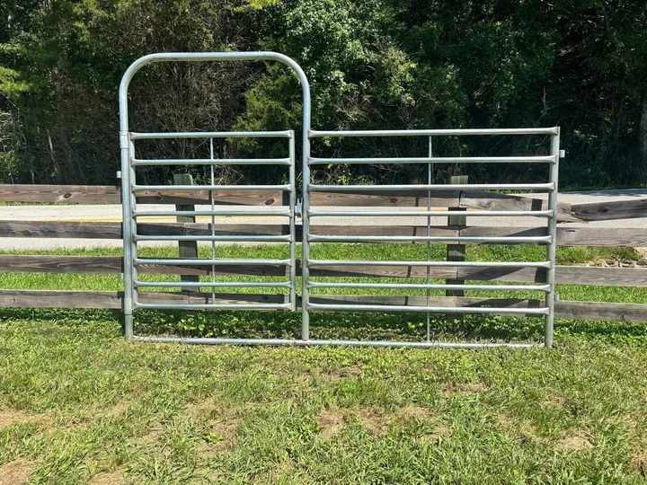 Galvanized 12-foot combo bow gate, half walk-through gate and half panel, in front of a wood fence