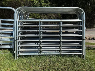 Galvanized 10-foot heavy bow gates stacked against a wood fence