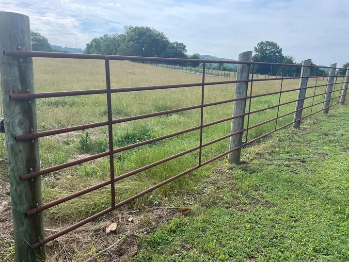 4x20 six-rail continuous fence panels installed along a pasture fence line