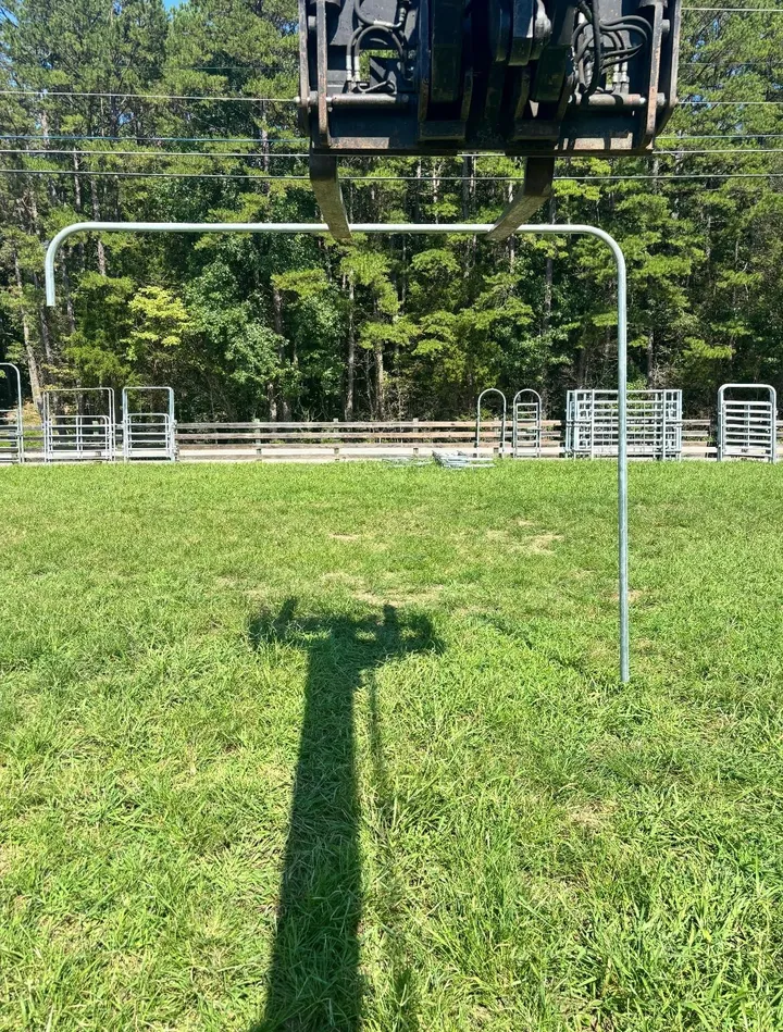 Galvanized top brace lifted by equipment above a pasture