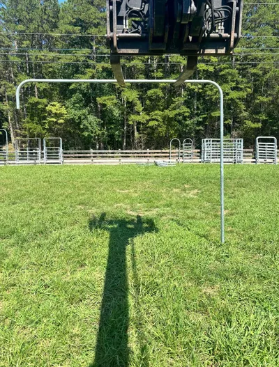 Galvanized top brace lifted by equipment above a pasture