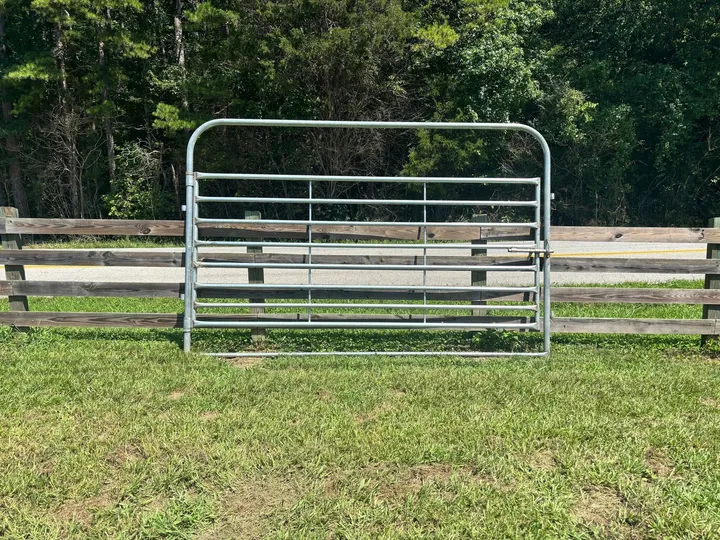 Galvanized 12-foot heavy bow gate in front of a wood fence
